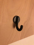 Black metal J-hook peg accessory mounted on birch plywood pegboard, designed for TexWoodBuilds pegboards, for hanging bags keys and accessories