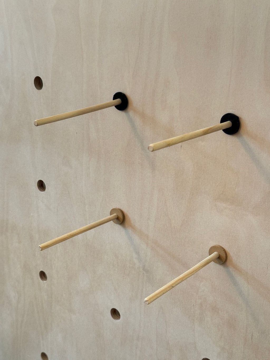 Quarter inch birch plywood pegs with black adapters installed in TexWoodBuilds large pegboard, CNC cut in our shop, designed for TexWoodBuilds pegboards